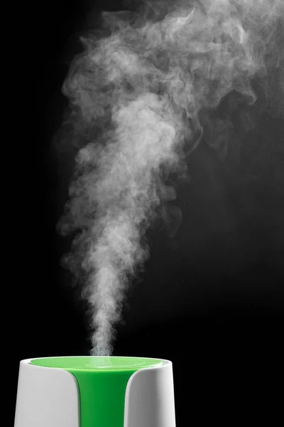 Ultrasonik nemlendirici delikten su buharı salıyor. Siyah arka planda. Ultrasonik nemlendiricinin işletim süreci..