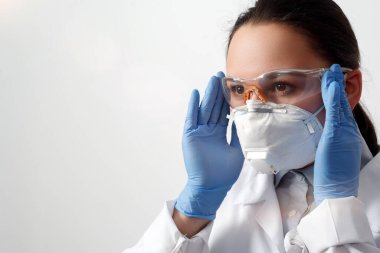 Koruyucu eldivenli, gözlüklü ve solunum maskeli bir kadın doktor portresi. beyaz arkaplanda