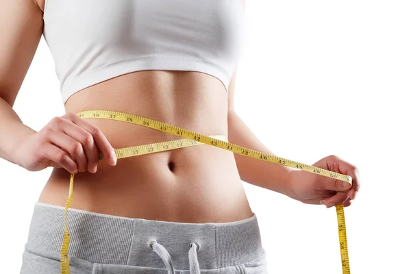 İnce bir kadının, belinin ölçüsünü şeritle ölçtüğü yakın plan. Beyaz arkaplanda izole.
