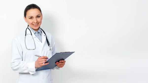女性医療従事者の肖像画です 白い背景にクリップボードを持つ若い医師 コピースペース — ストック写真