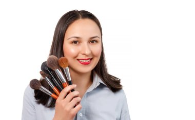 Makyaj fırçasıyla genç bir kadın makyaj sanatçısının portresi kameraya bakar ve gülümser. beyaz arkaplanda izole edilmiş.