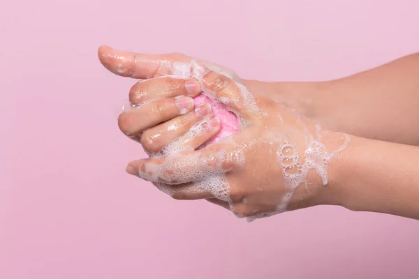 Hygiene to protect human health from viruses, hand washing with soap process. On pink background.