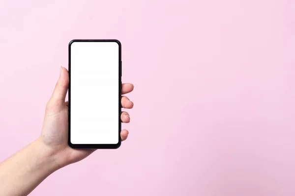 Akıllı telefonun kullanım konsepti. Elinde beyaz bir ekranı olan akıllı bir telefon bir kadının ellerinde. Pembe bir arka planda.