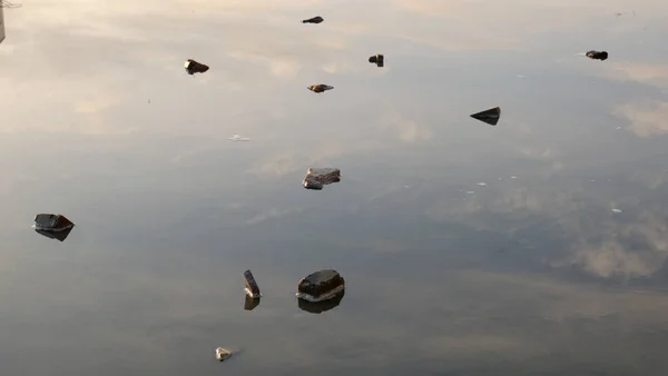 Steine, die in einem Teich liegen und den klaren Himmel reflektieren. — Stockfoto