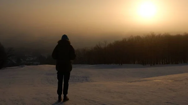 Soğuk bir sabah güneşin doğuşunu bakarak adam (genç erkek).