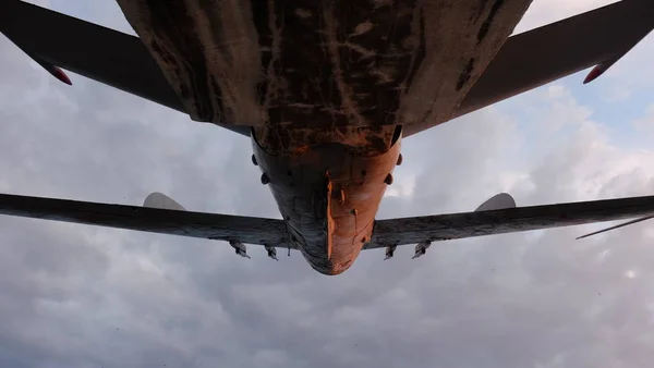 The fuselage of an airplane in the background of a cloudy sky.