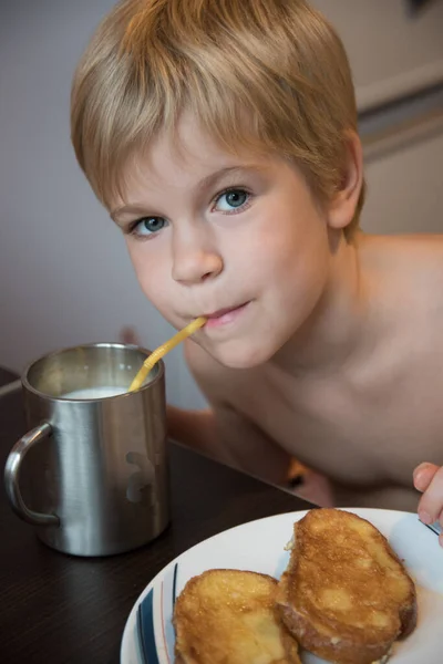 Dítě pije mléko u snídaně. Mléko a krutony. — Stock fotografie