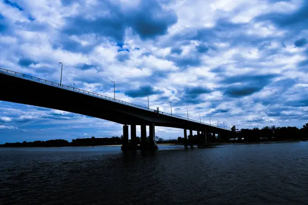 Puente de carretera grande sobre el río, contrastando nubes y cielo azul, dramático — Foto de Stock