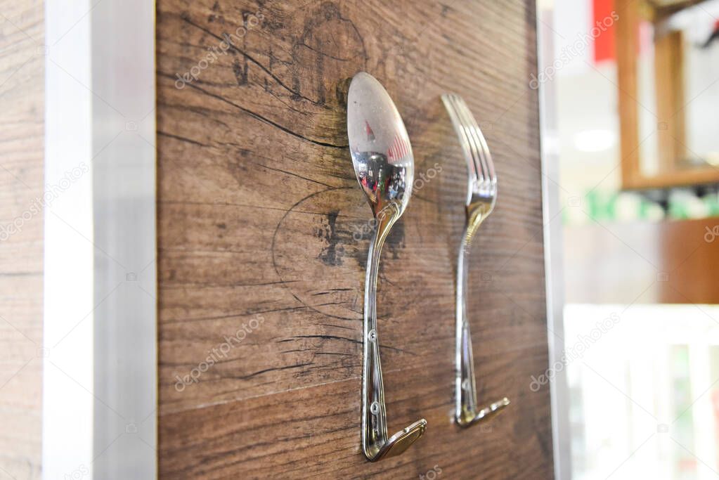 Spoon and fork as hooks for clothes. The decor of the restaurant, coffee shop.