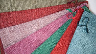 Beyaz arka planda farklı renkte hediyeler paketlemek için kumaş torbaları. Kalp şeklinde dantel.