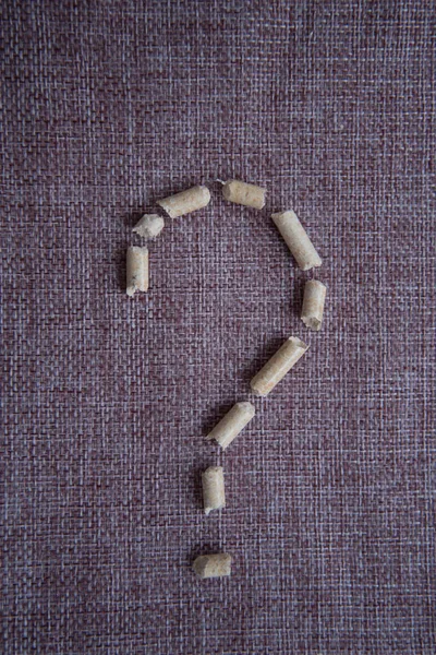 The question mark, built of wood pellets for heating. Concept. Benefit. Question mark, lined with wood filler for the cat tray.