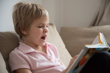 Çocuk esniyor ve büyük bir kitap okumaktan sıkılıyor. Kavram.