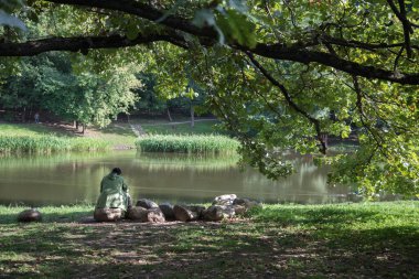 Yalnız bir adam nehir kıyısındaki bir kayanın üzerinde oturuyor. konsept. Yalnızlık.