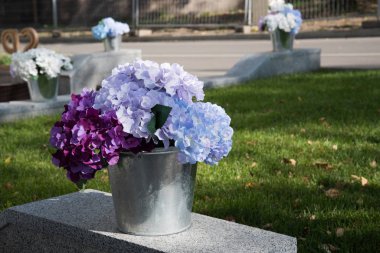 Küçük kovalardaki güzel yapay çiçekler halka açık bahçelerdeki yolların güzelliklerini süslemek için dururlar..