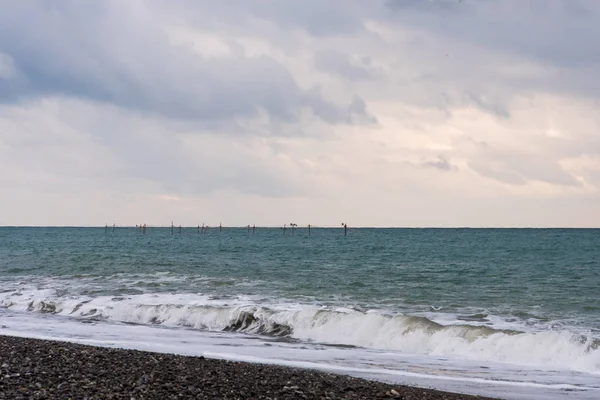 Una pequeña granja de ostras y mejillones en la costa del mar negro. Las estructuras agrícolas son visibles en el mar, y una tormenta de olas de 4 puntos está en primer plano. El cielo claro . —  Fotos de Stock