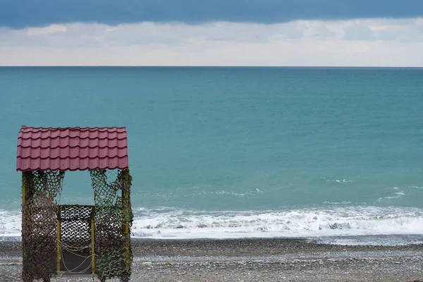 Ein einsamer Rettungsturm steht an der Küste. Der Hintergrund ist ein Meer von erstaunlichen Farben. Nebensaison, Winter. — Stockfoto