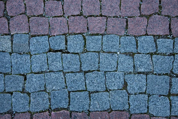 Paving stones made of natural stone. Paths for pedestrians. Beautiful multi-colored square-shaped stones. The view from the top. Background — ストック写真