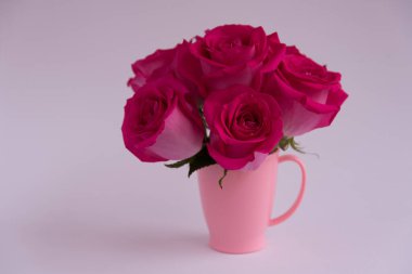 Açık arkaplanda pembe güller. Bir buket çiçek pembe bir kupada duruyor. Pembe vazo. Şık bir buket.