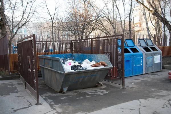 A large garbage can standing in the courtyards of residential buildings. Garbage is placed in a specially fenced area. Courtyard in the city.