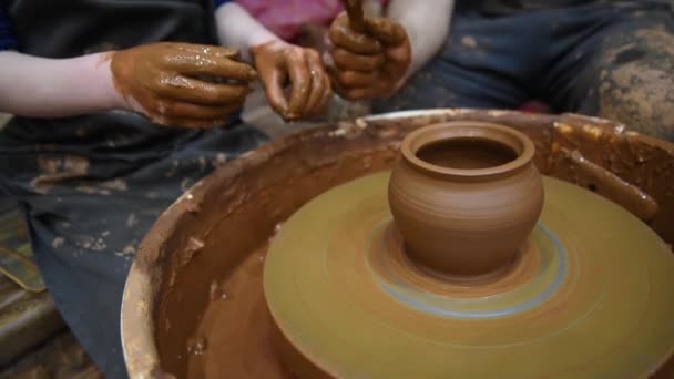 Roue de potiers. Il y a deux personnes qui travaillent derrière le volant de Potters : un adulte et un enfant. Un adulte enseigne la poterie à un enfant. Faire un pot d'argile. Concept, aide et formation . — Video