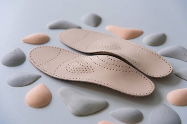 Parçalarla çevrili bir çift deri ortopedik taban. Farklı şekil ve boyutlardaki çapraz kemeri boşaltmak için pelotlar. Tercih. Ayak hastalıkları ve düz tabanlar için bireysel ortopedik taban üretimi süreci. & Yakın plan