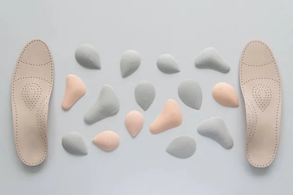 A pair of leather orthopedic insoles surrounded by components. Pelots for unloading the cross arch of different shapes and sizes. Choice. — Stock Photo, Image