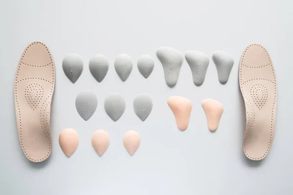 A pair of leather orthopedic insoles surrounded by components. Pelots for unloading the cross arch of different shapes and sizes. Choice. — Stock Photo, Image