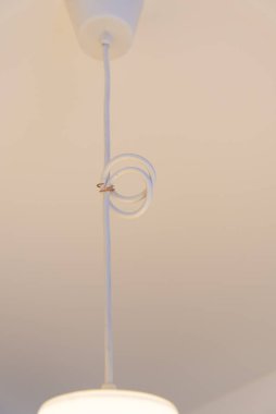 Elektrik kablosuna asılı beyaz bir avize. Kablo bir halkada monte edilmiş bir hisse senedi var. Stok konsepti