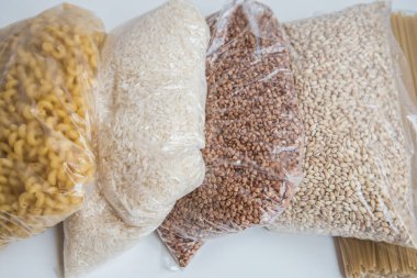 Bej arka planda gıda bağışları, şeffaf torbalarda mısır gevreği ve makarna..