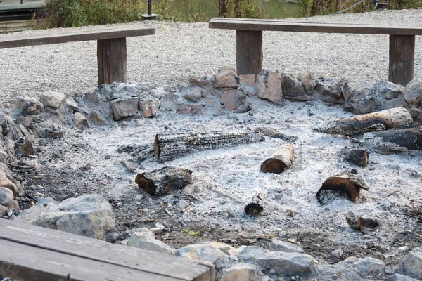 Fire pit with ashes. Clearing. There are benches all around.