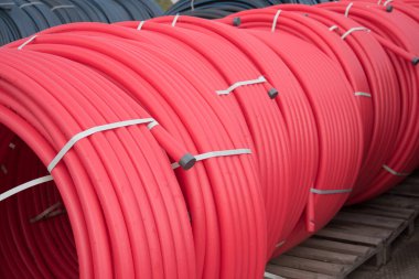 Kırmızı plastik borular açık hava rulolarına sarılmış. İnşaat alanı
