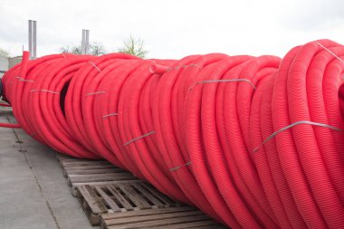 Kırmızı plastik borular açık hava rulolarına sarılmış. İnşaat