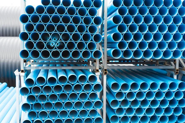 Blue plastic pipes laid on special metal shelving. Production and marketing pipes