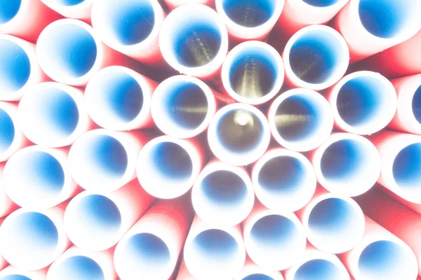 A lot of plastic pipes. The pipes are red outside and blue inside. Warehouse
