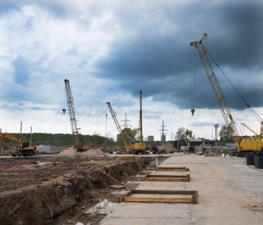 Kule vinçleri olan bir inşaat alanı. Lastikleri monte edilmiş çukur. Kule vincleri ve gökyüzü.