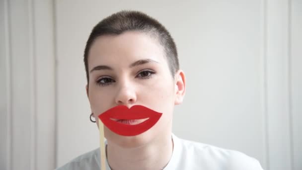 Ein Mädchen Mit Kurzen Haaren Probiert Riesige Rote Lippen Konzept — Stockvideo