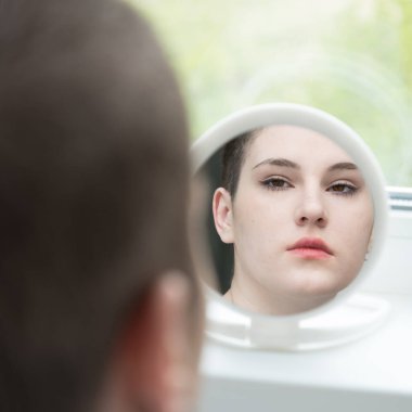 Güzel kel bir kız aynada kendine bakıyor. Barış