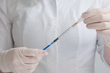 Doktor şırınganın içindeki sıvıyı çevirir. Bakım ve önleme kavramı. Aşılama. İnsülin şırıngası