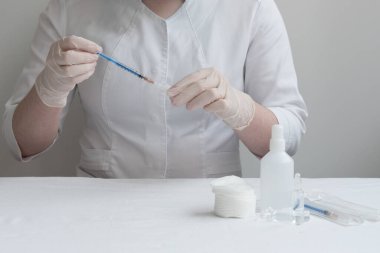 Doktor şırıngaya ilaç ya da aşı bağlıyor. Doktorun önünde, enjeksiyon için gereken her şey masaya yatırıldı. İnsülin şırıngası..