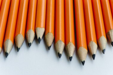 Geri okul kavramı. Bir sürü üst üste bir tablo üzerinde turuncu kalemler.