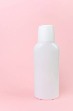 Pastel pembe arka planda beyaz şişe. Kozmetik şişe, mocap için resimler. Minimalizm, metin için yer.