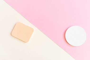 Bej ve pembe arka planda kozmetik süngerler. Yüz ve vücut bakımı kavramı, kozmetoloji. Minimalizm, üst görüş. Kopyalama alanı