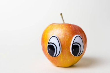 Gözü yana bakan kırmızı elma. Meyvelerin komik şirin resmi. Hafif arkaplan, metin için yer.