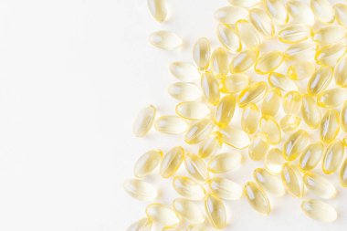 Açık renkli arka planda şeffaf sarı vitamin kapsülleri. Sağlık konsepti, güzellik. E vitamini, omega-3, D3 vitamini, balık yağı. Üst görünüm, minimalizm, kopyalama alanı.