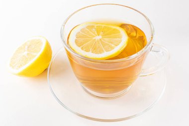 Herbal lemon tea in a transparent cup and saucer. Nearby are dried herbs and flowers, lemon. Light pastel background. The concept of healthy organic drinks.