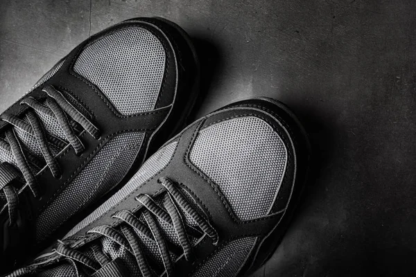Black sports gym shoes close-up. The concept of comfortable casual shoes. Dark background, minimalism, copyspace, top view, flat lay.