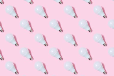 Öncü ampuller pastel pembe arka planda yatar. Enerji tasarrufu kavramı. Minimalizm, üst görünüm, düz görünüm, metin için yer, desen.