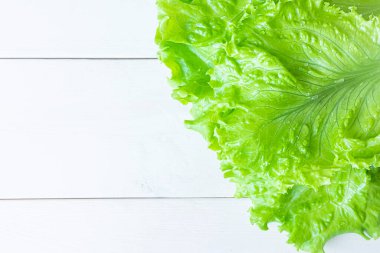 Beyaz ahşap arka planda taze sulu marul salatası. Sağlıklı beslenme, vejetaryenlik kavramı. Üst görünüm, minimalizm, kopyalama alanı.