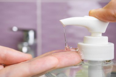 Sıvı sabun makinesi ve lavabonun arka planında bir erkek eli. Yakın plan. Temizlik, hijyen, hastalıklara ve virüslere karşı koruma kavramı.