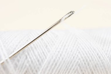 İğneli beyaz iplik. Ayrıntılı makro fotoğraf. Dikiş dikme, atölye, hobiler, ödevler.